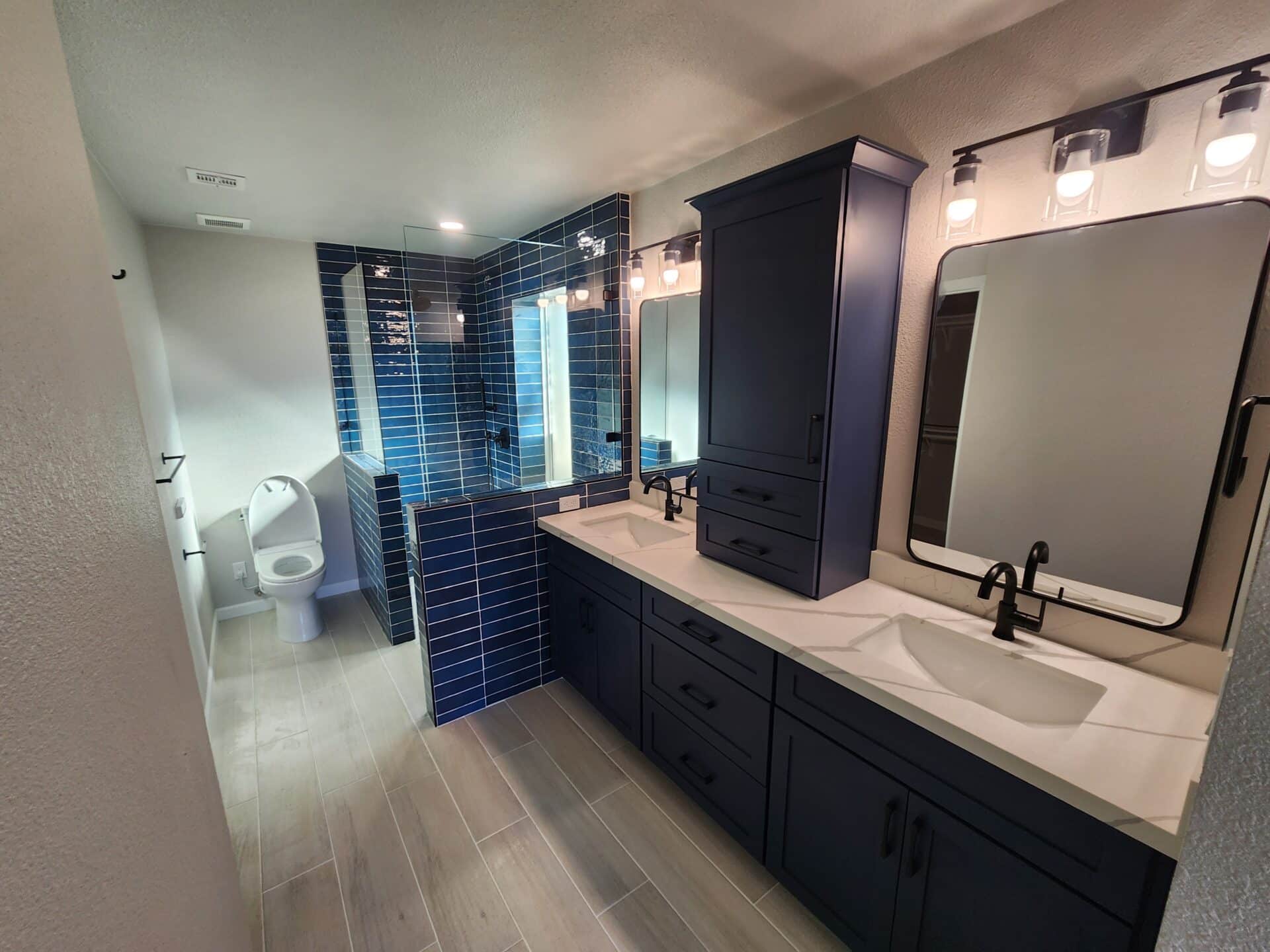 Navy double vanity and blue tile shower in a completed Chandler bathroom